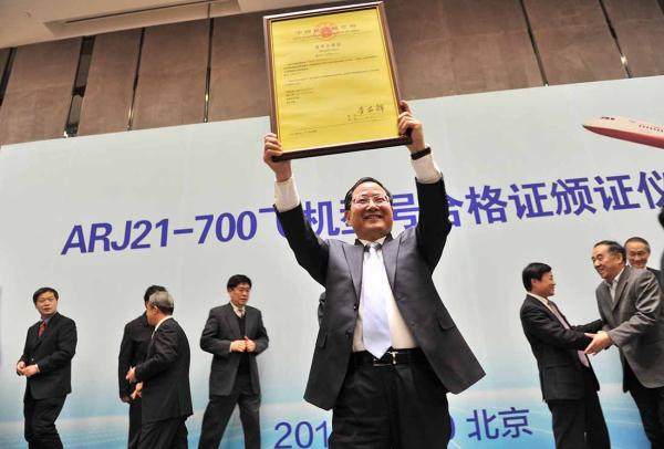 12月30日,中國商飛公司董事長金壯龍展示ARJ21-700飛機型號合格證。新華社 圖